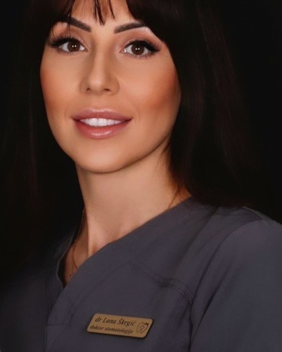 Dr Lana Škrgić u radnoj uniformi sa pločicom „dr Lana Škrgić, doktor stomatologije”